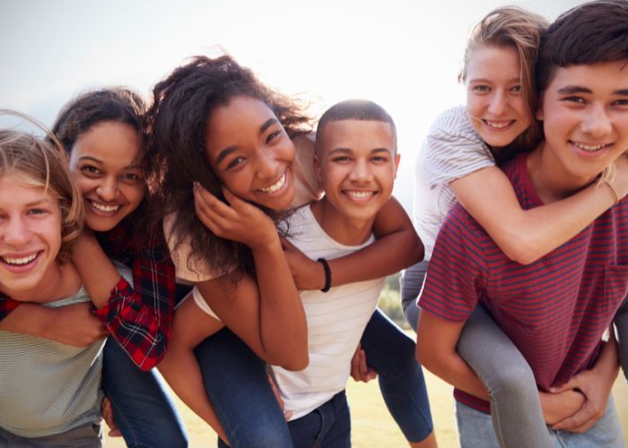 Happy teens spending time together outdoors, reflecting emotional well-being, strong relationships, confidence, and positive youth development.