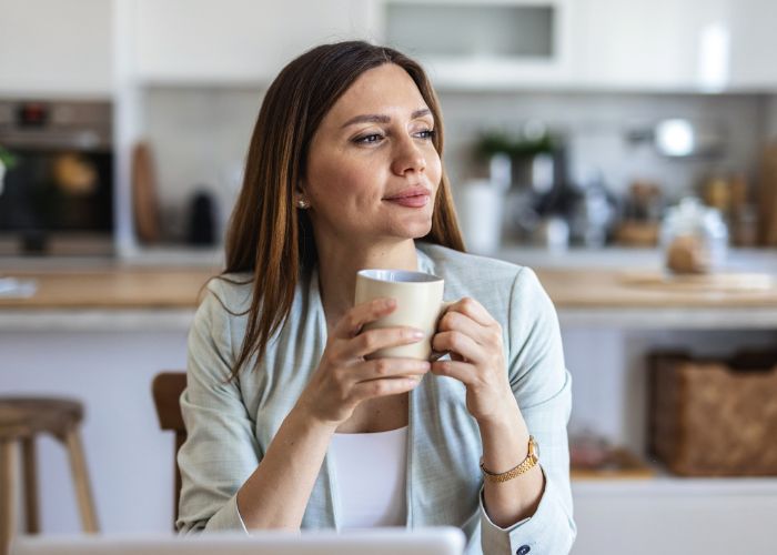 Woman pausing with a warm drink, representing the power of the pause and intentional living for overwhelmed moms Joyful Reinvention with Maria Hendershot